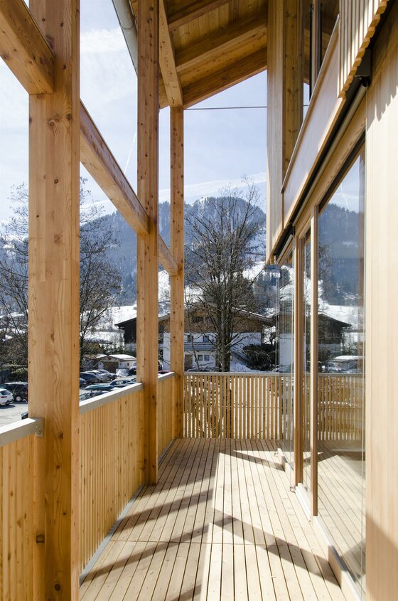 Holzbalkon mit Blick auf schneebedeckte Berge und ein Dorf.