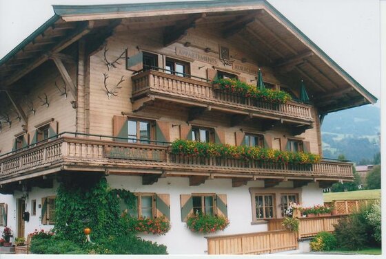 Hausansicht Auracherhof im Sommer Alpines Holzhaus mit Blumenbalkonen und Geweihen an der Fassade.