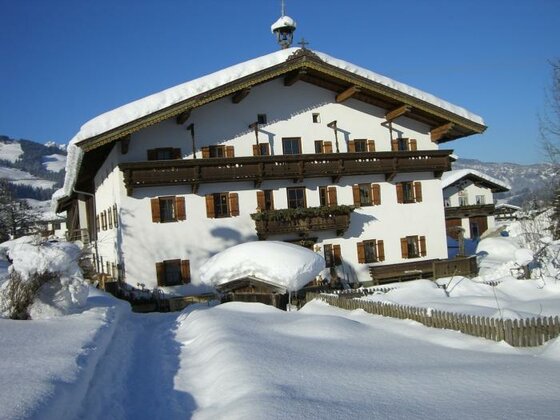 Seiwaldhof Winter Ein charmantes, weißes Haus mit Holzverzierungen, umgeben von Schnee. Der klare blaue Himmel und die verschneite Landschaft schaffen eine idyllische Winteratmosphäre.