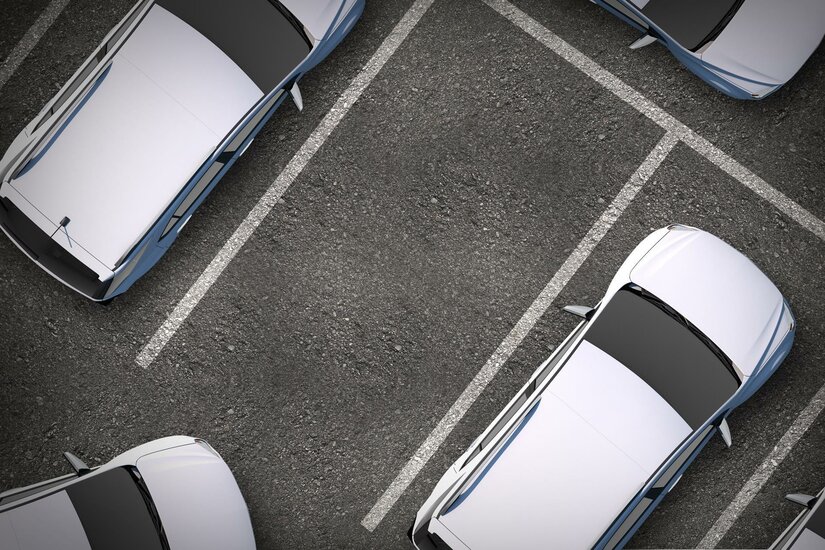 Hertz Eine Vogelperspektive auf einen Parkplatz mit mehreren weißen Autos. Die Parklücken sind deutlich sichtbar.