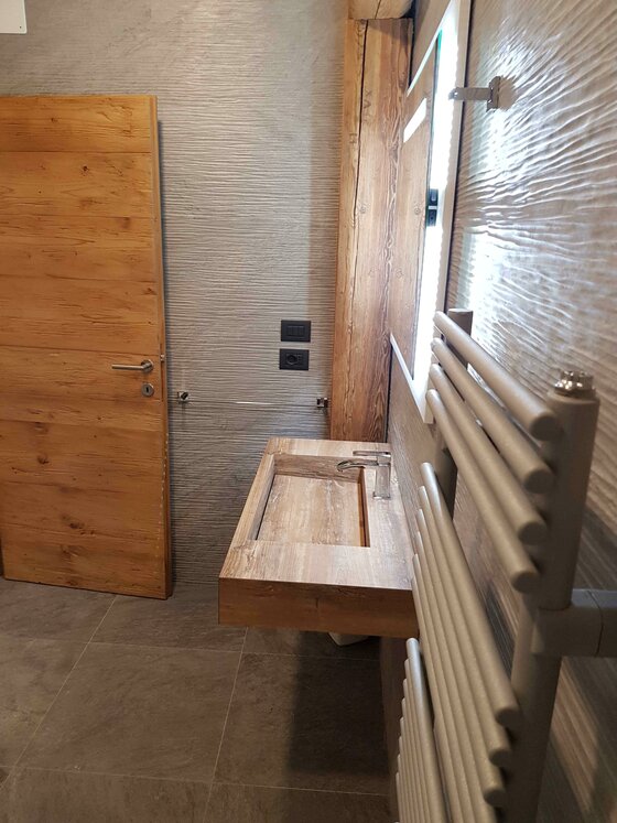 Badezimmer im Apartment Südberge Modernes Badezimmer mit Holzwaschbecken, Holztür und Handtuchheizkörper.