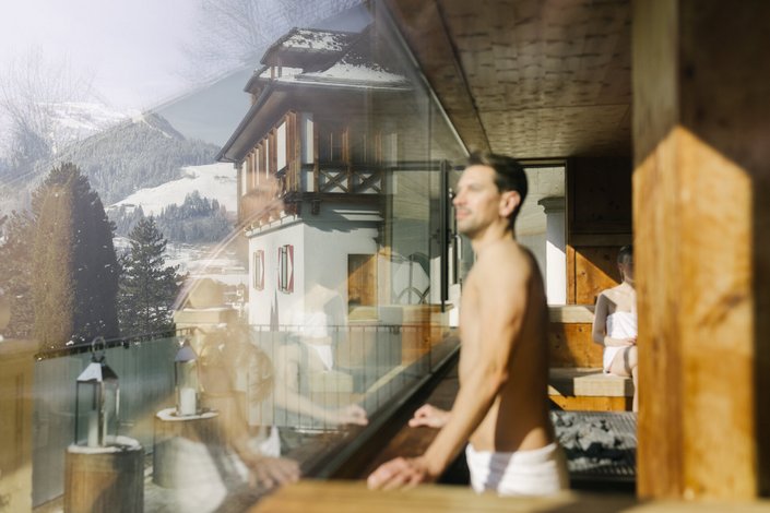 Ein Herr genießt die Aussicht aus einer Panorama Sauna 