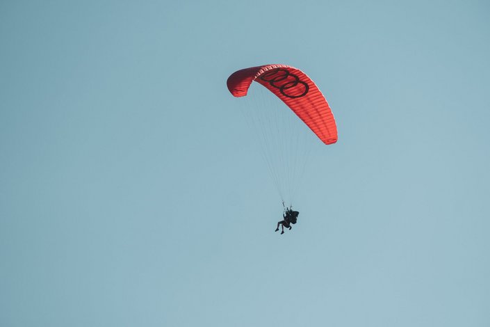 Paragleiter mit rotem Schirm in der Luft