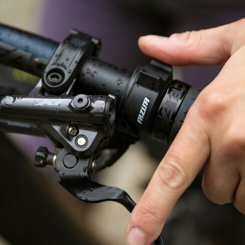 Eine Hand greift auf einem FAZUA-betriebenen E-Bike in Kitzbühel nach dem Bremshebel am Lenker.
