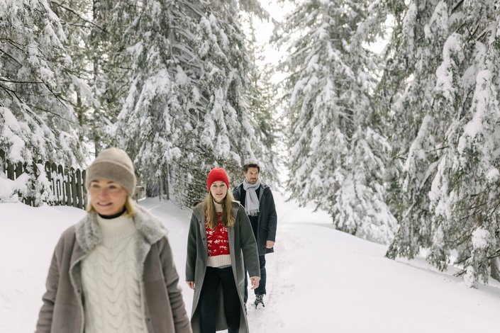 Family goes winter hiking in the snowy fir forest