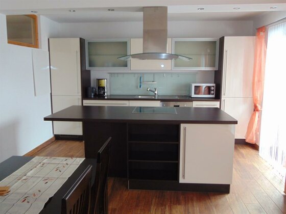 Moderne Einbauküche mit Kochinsel, dunkler Arbeitsplatte und hellen Fronten in einem Apartment.