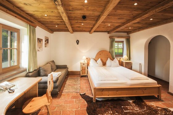 Rustikales Schlafzimmer mit Doppelbett, Holzdecke, Sofa und Schreibtisch.