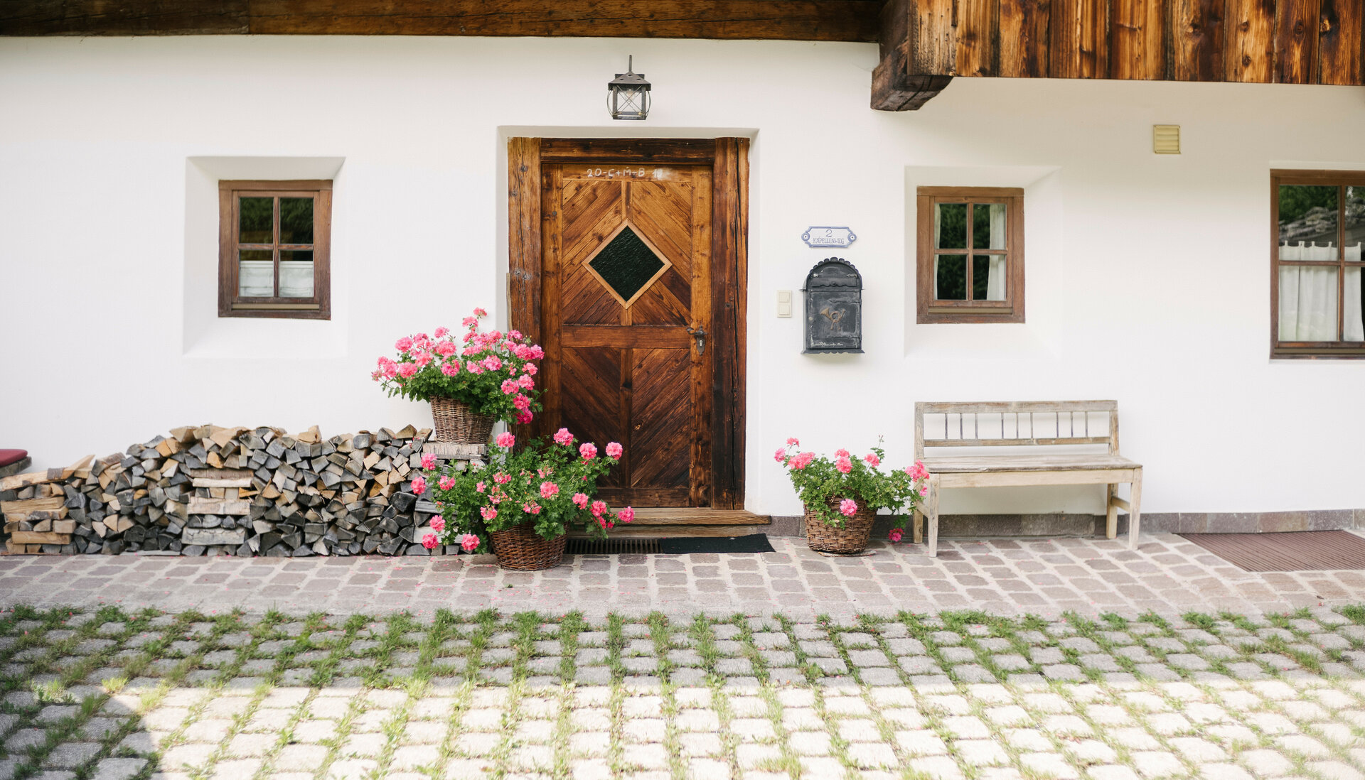 Die Fassade des Hauses zeigt eine einladende Atmosphäre mit einer Holzbank, Blumen und einem traditionellen Briefkasten.