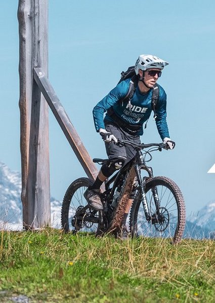Ein Mann auf dem Rad, grüne Wiese und Berge im Hintergrund