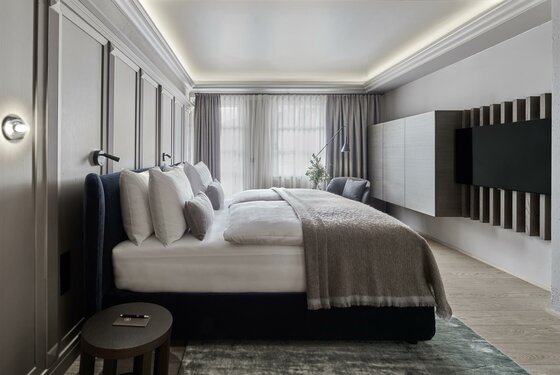 Deluxe Suite Residenz Modernes Hotelzimmer mit Doppelbett, Wandpaneelen und Fernseher.