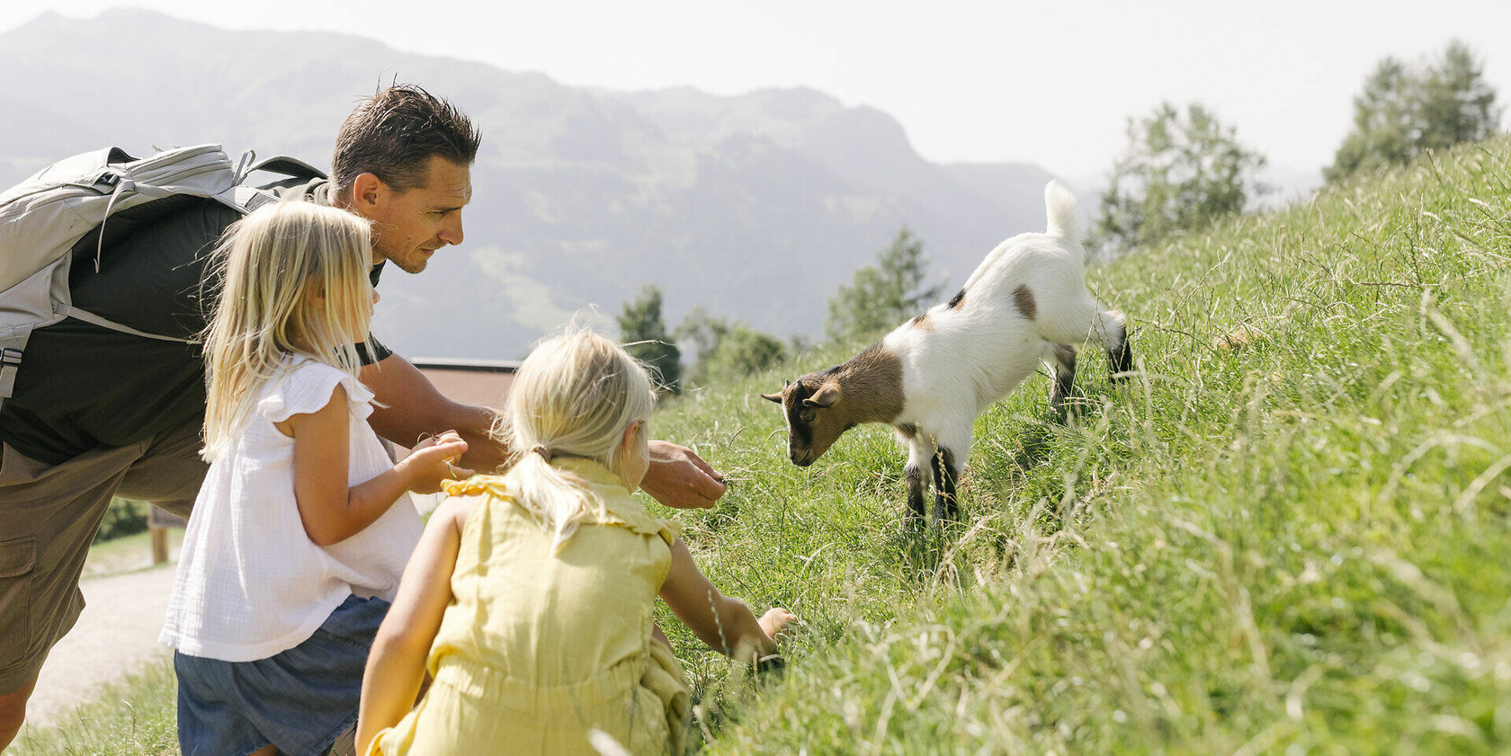 Familie Wildpark Aurauch Vater und zwei Töchter füttern ein Ziegenjunges im Wildpark Aurach bei Kitzbühel.
