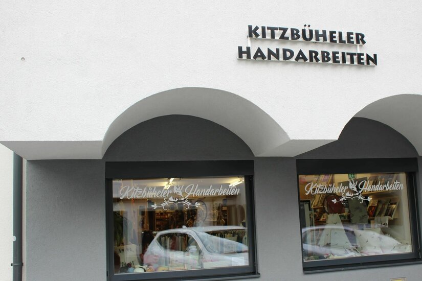 Außenansicht eines Ladengeschäfts mit der Aufschrift Kitzbüheler Handarbeiten über zwei Schaufenstern.