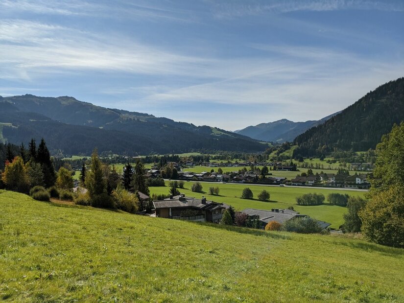 Blick auf Bichlach Blick von einer grünen Wiese auf ein Dorf im Tal vor bewaldeten Bergen unter blauem Himmel.