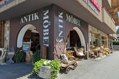 Eingangsbereich eines Geschäfts für Antikmöbel mit Rundbögen, Holzkarren und Geweihen.