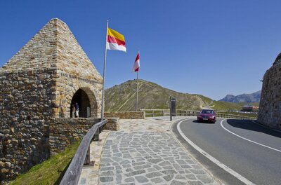 Fuscher Törl Großglockner Hochalpenstraße Steinerner Turm am Fuscher Törl neben der Großglockner Hochalpenstraße mit Flaggen und einem Auto.