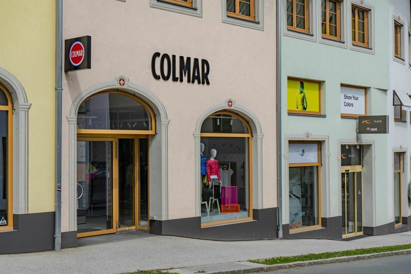 Sportgeschäft Colmar Außenansicht eines Sportgeschäfts mit Schaufenstern und Colmar-Schriftzug an einer hellen Fassade.