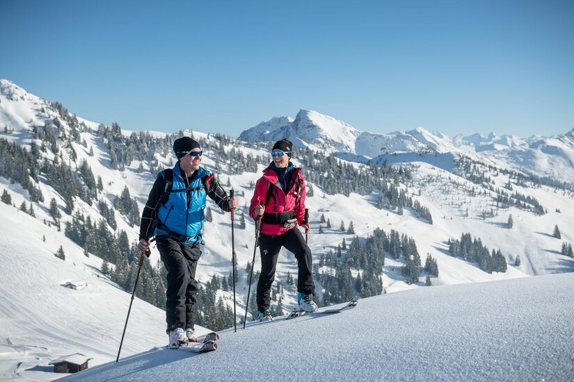 Skitour auf der Bichlalm Zwei Skitourengeher auf einem verschneiten Bergrücken vor alpinem Panorama.