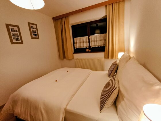 Ein gemütliches Schlafzimmer mit einem Doppelbett und zwei Kissen. Weiche Farben und warme Beleuchtung sorgen für eine entspannte Atmosphäre.