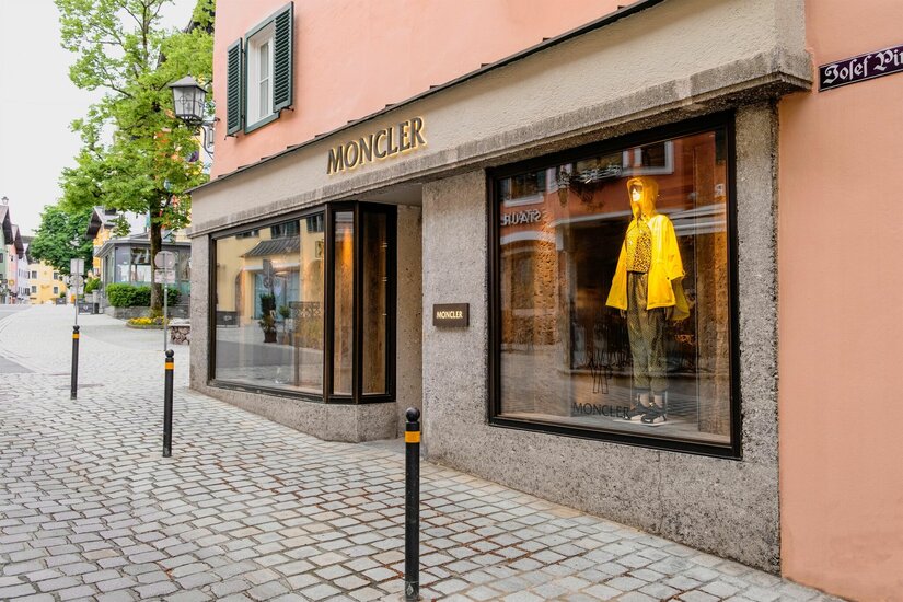 Moncler Boutique Außenansicht eines Moncler-Geschäfts in einer gepflasterten Fußgängerzone mit Schaufensterpuppe.