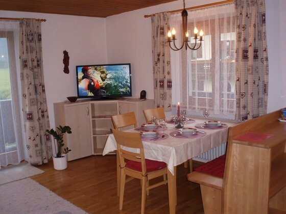 Essbereich im Apartment Essbereich mit gedecktem Holztisch, Stühlen, Eckbank und einem Fernseher im Hintergrund.