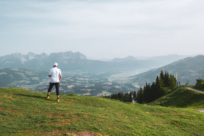 Ein Mann im weißen T-Shirt schaut vom Hahnenkamm runter