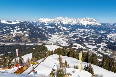 Winterpanorama von der Hocheckhütte Blick von der verschneiten Hocheckhütte auf ein weites Tal und schneebedeckte Berggipfel unter blauem Himmel.