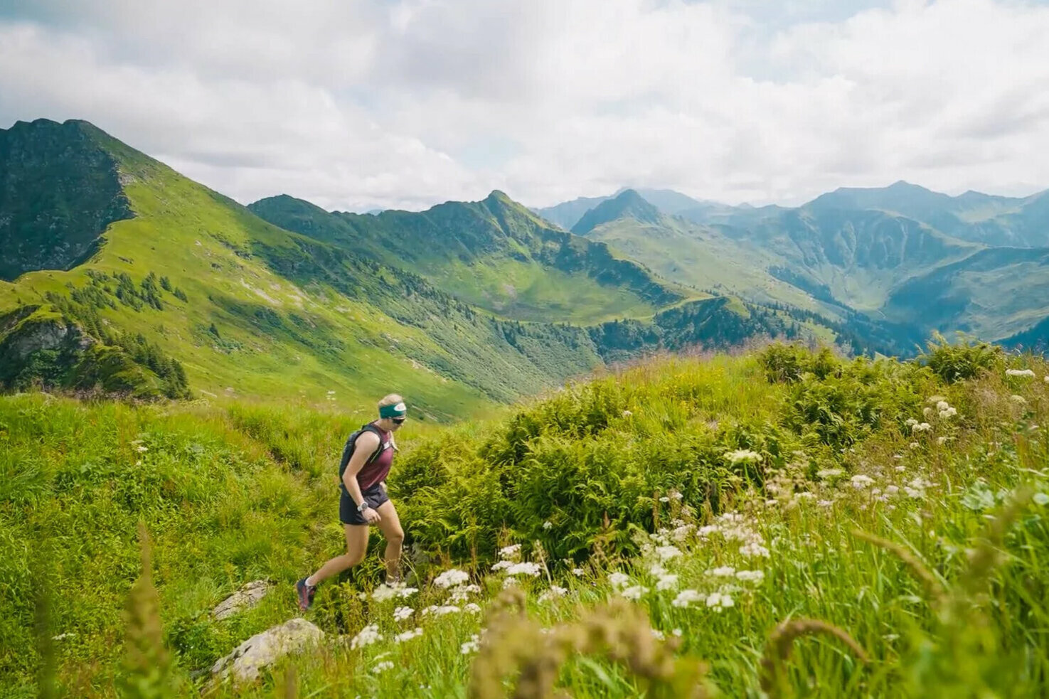 A woman is walking across lush alpine meadows in Kitzbühel