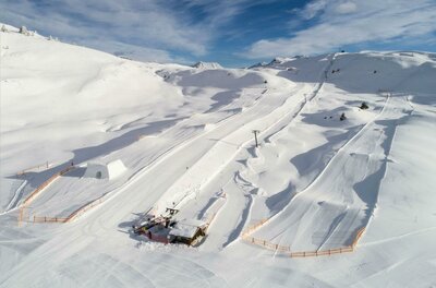 SnowparkHorn Eine schneebedeckte Landschaft mit Skihängen und einem kleinen Skilift. Der Himmel ist klar und blau, ideal für Wintersport.