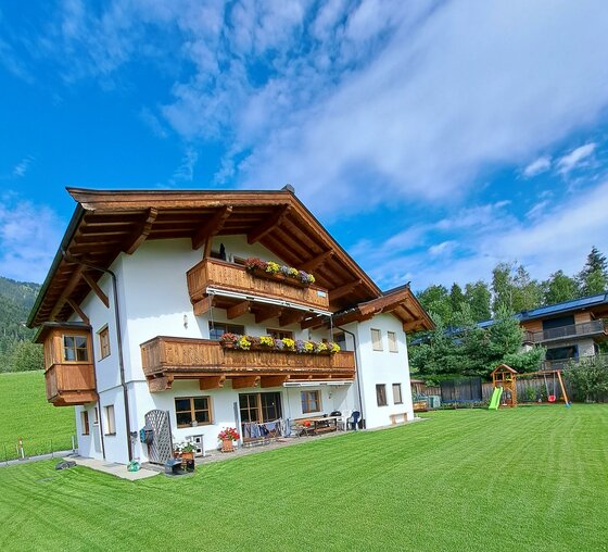 20250730_161434 Ein schönes, traditionelles Haus mit Holzbalkonen in einer grünen Umgebung.