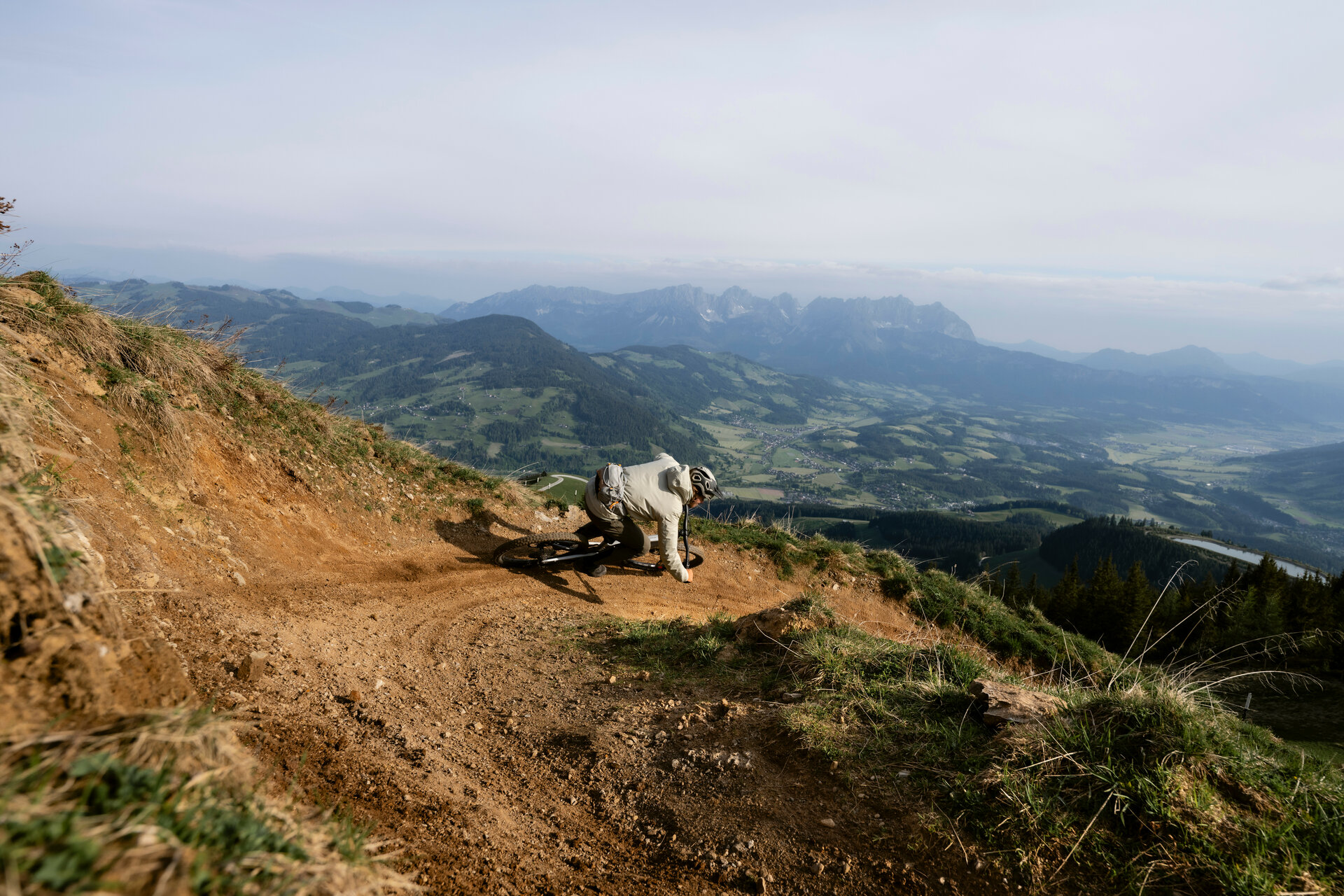 Ein Mountainbiker fährt bei den 360 Flow Trails in Kitzbühel mit Schwung eine kurvenreiche Strecke an einem Berghang mit Aussicht auf die umliegenden Berge.