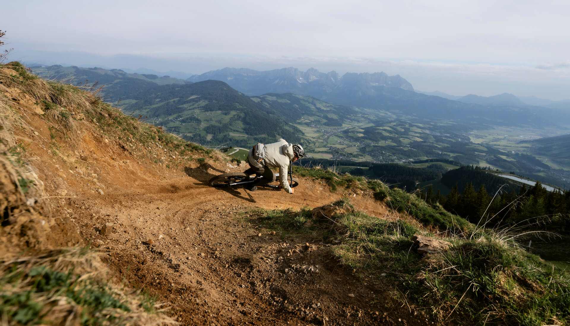 Ein Mountainbiker fährt bei den 360 Flow Trails in Kitzbühel mit Schwung eine kurvenreiche Strecke an einem Berghang mit Aussicht auf die umliegenden Berge.