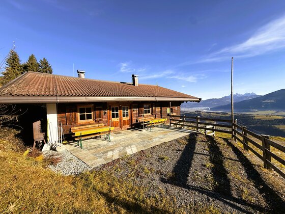 Wirtsalm Eine gemütliche Hütte mit Holzverkleidung und großen Fenstern. Die Terrasse bietet einen Blick auf die Berglandschaft und die umliegende Natur.