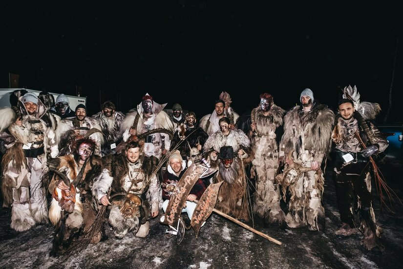 Gruppe von Männern in traditionellen Krampus-Kostümen aus Fell und Masken bei Nacht.