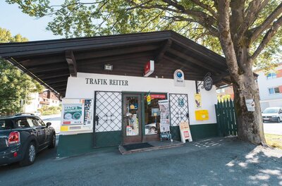 Trafik Reiter Außenansicht Außenansicht der Trafik Reiter in einem flachen Gebäude mit dunklem Holzdach und Zeitungsständern vor dem Eingang.