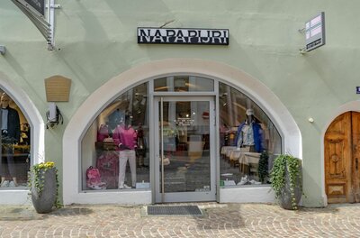 Eingangsbereich eines Bekleidungsgeschäfts mit Rundbogenfenster und Schaufensterpuppen.