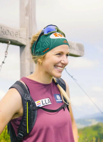 Lisa Hauser in front of a summit cross on the mountain