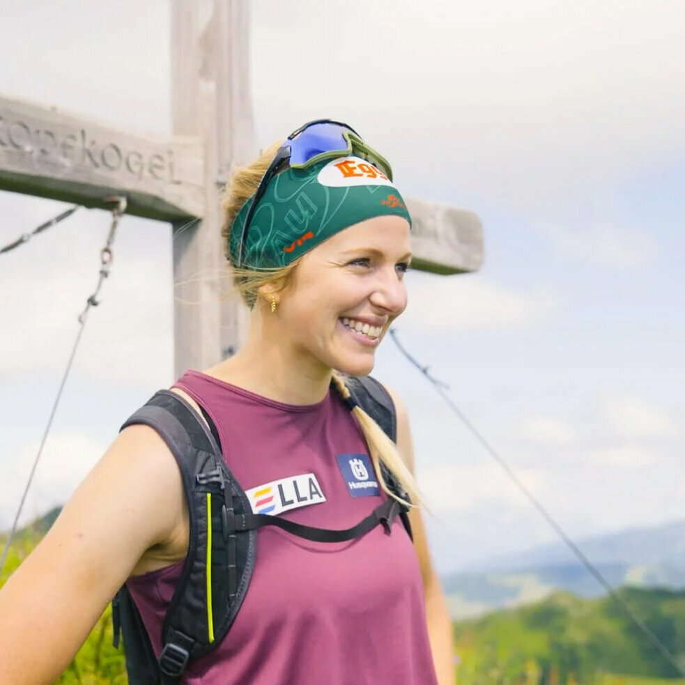 Lisa Hauser in front of a summit cross on the mountain