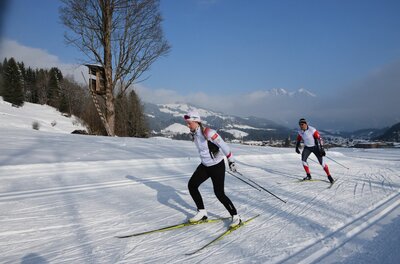 Langlauf auf der Sportloipe Zwei Personen beim Skilanglauf auf einer präparierten Loipe in einer verschneiten Berglandschaft.