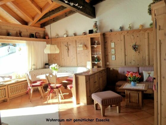 Wohnraum Landhaus Perktold Rustikaler Wohnraum mit holzgetäfelten Wänden, einer Eckbank am runden Esstisch und einer kleinen Sitzecke.
