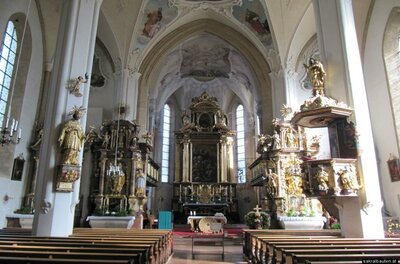 Eine wunderschöne Kirche mit reichhaltiger Innenausstattung und hohen Decken. Die Bänke sind aufgereiht und es gibt kunstvolle Altäre an den Wänden.