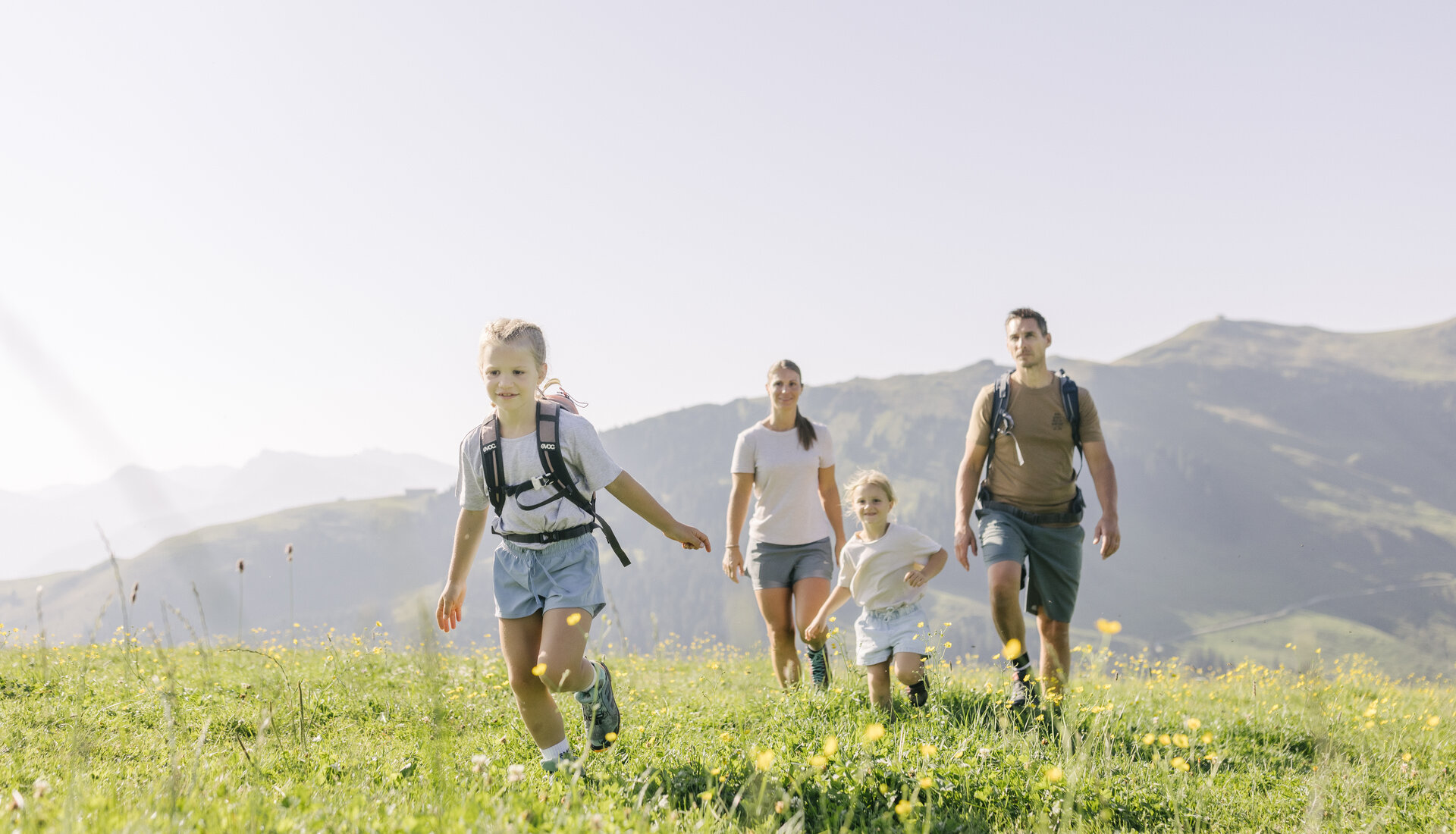 Eine Familie spielt auf einer Blumenwiese in den Bergen
