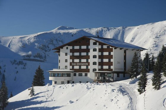 Hotel Ehrenbachhöhe im Winter Mehrstöckiges Hotelgebäude in einer verschneiten Gebirgslandschaft unter blauem Himmel.