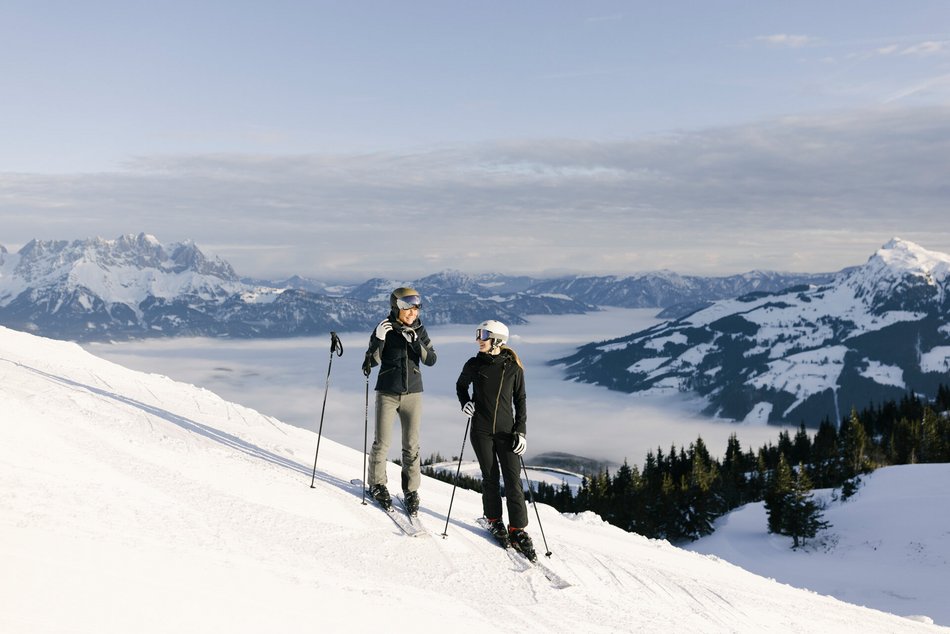 A couple stands on the mountain with skis in the snowy landscape