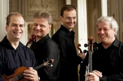 Sommerkonzert1208 Eine musikalische Darbietung auf einer Bühne mit vier Musikern. Das Publikum applaudiere und genießt die Aufführung.