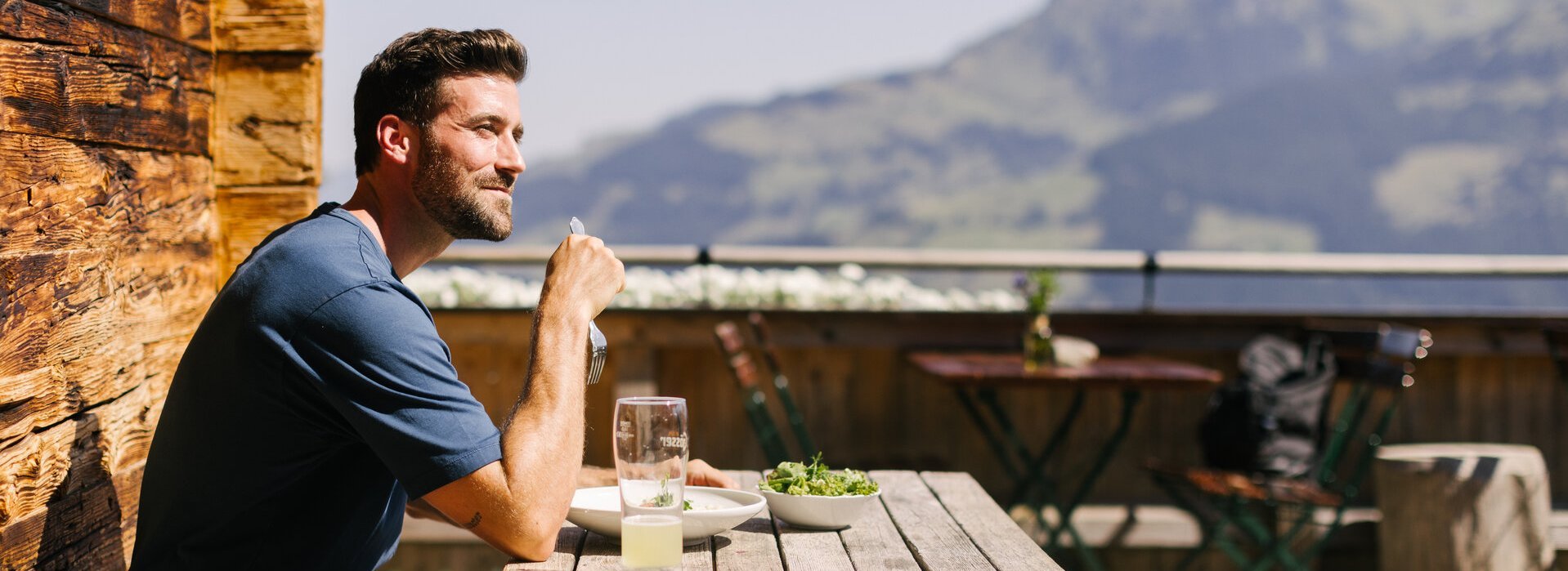 Mann genießt sein Essen auf einer Hütte in Kitzbühel im Sommer
