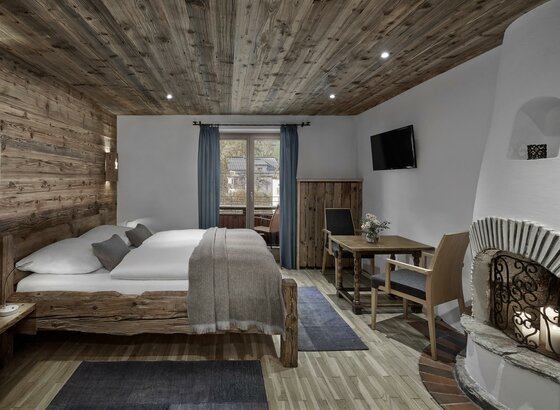 Hotel Goldener Greif Doppelbettzimmer Rustikales Hotelzimmer mit Doppelbett aus Altholz, Sitzecke und offenem Kamin.