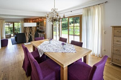 Essbereich im Landhaus Kitzhorn Holztisch mit lila Stühlen in einem hellen Wohn- und Essbereich mit Parkettboden.