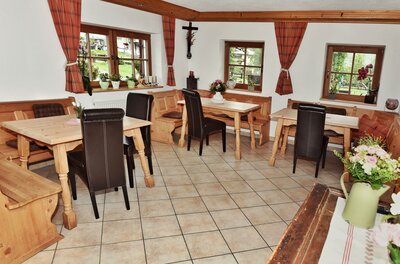 Gastraum im Astlingerhof Rustikaler Gastraum mit Holztischen, Eckbänken und dunklen Lederstühlen auf Fliesenboden.