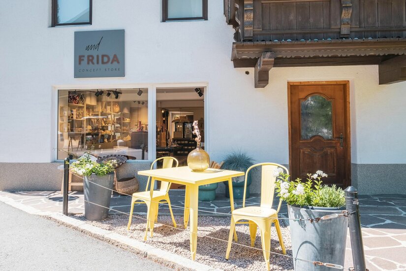 Concept Store undFRIDA Außenansicht des Concept Stores undFRIDA mit gelben Metallstühlen und einem Tisch vor dem Schaufenster.