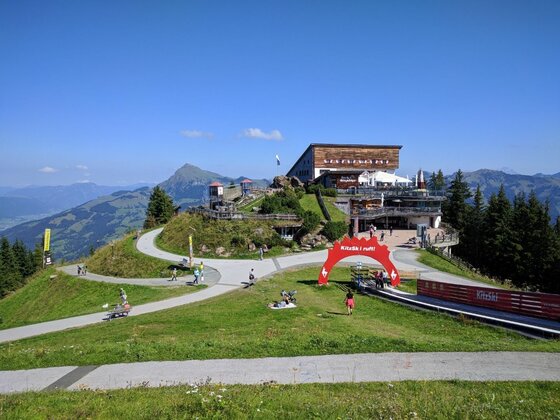 Bergstation der Vier-Seen-Wanderung Blick auf eine Bergstation mit Wanderwegen, rotem Torbogen und Bergpanorama unter blauem Himmel.